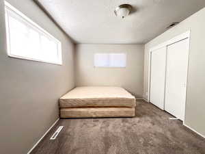 Bedroom with a closet, a textured ceiling, and carpet flooring