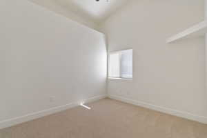 Carpeted main floor bedroom room featuring vaulted ceiling