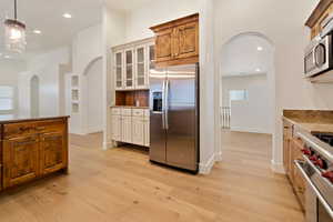 Kitchen with stainless steel appliances, hanging light fixtures, light wood flooring, and granite counter tops