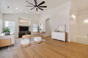 Living room with light hardwood / wood-style floors, high vaulted ceiling, and ceiling fan. Virtually Staged