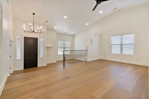 Entryway with light hardwood / wood-style floors, high vaulted ceiling, and ceiling fan with notable chandelier