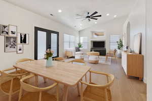 Dining room with french doors, ceiling fan, vaulted ceiling, and light hardwood / wood-style flooring. Virtually staged