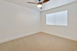 Carpeted spare room featuring ceiling fan