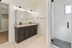 Primary Bathroom featuring an enclosed shower, double sink vanity, and tile floors