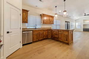 Kitchen with dishwasher, lofted ceiling, ceiling fan, light wood flooring, and pendant lighting