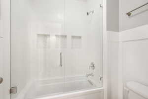 Bathroom featuring enclosed tub / shower combo and toilet