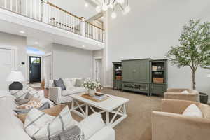 Living room with a high ceiling and light carpet