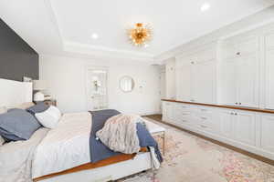 Bedroom featuring ensuite bathroom, ornamental molding, and a tray ceiling