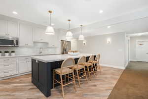 Kitchen with backsplash, appliances with stainless steel finishes, a center island, and light hardwood / wood-style flooring