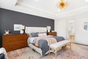 Bedroom with a tray ceiling, crown molding, and connected bathroom