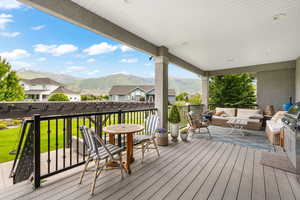 Deck featuring an outdoor living space, a lawn, and a mountain view