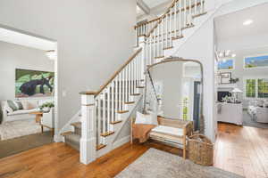 Stairs with wood-type flooring, a towering ceiling, and a chandelier