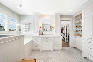 Bathroom with tile floors, tiled tub, ornate columns, and vanity