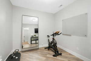 Exercise room with light hardwood / wood-style floors