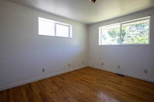 Empty room with a wealth of natural light and dark hardwood / wood-style flooring