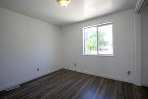 Spare room with dark wood-type flooring