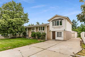 Tri-level home with a front lawn, a garage, and an outdoor structure