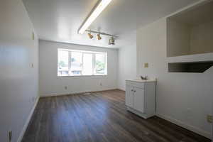 Spare room featuring track lighting and dark wood-type flooring