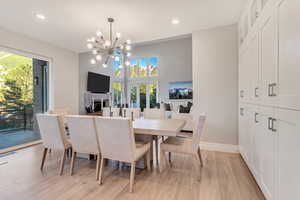 Dining room with light hardwood / wood-style floors and a notable chandelier