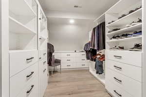 Spacious closet with light hardwood / wood-style flooring