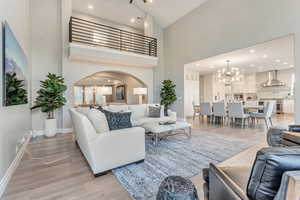 Living room with high vaulted ceiling, an inviting chandelier, and light hardwood / wood-style floors