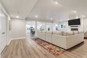 Living room with brick wall, a brick fireplace, and light hardwood / wood-style floors