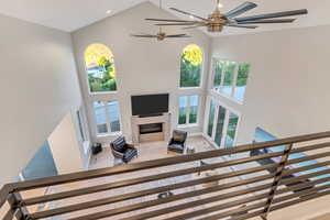 Stairway with high vaulted ceiling, ceiling fan, and hardwood / wood-style floors