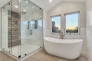 Bathroom featuring shower with separate bathtub, vaulted ceiling, and tile walls