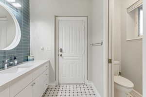 Bathroom featuring tile flooring, backsplash, toilet, and large vanity