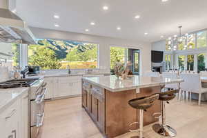 Kitchen with plenty of natural light, range with two ovens, a kitchen island, white cabinets, and range hood