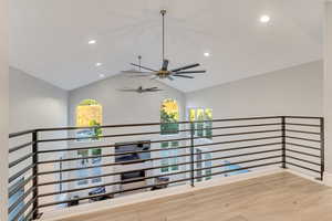 Corridor with vaulted ceiling and hardwood / wood-style floors