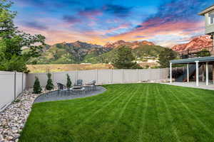 Yard at dusk with a patio area, a deck with mountain view, and a fire pit