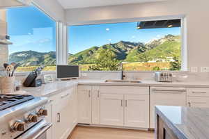 Kitchen featuring light stone counters, white cabinetry, light wood-type flooring, and a mountain view