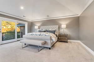 Carpeted bedroom featuring ornamental molding, vaulted ceiling, and access to exterior