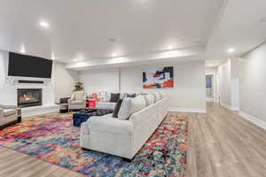 Living room with hardwood / wood-style flooring, a fireplace, and brick wall