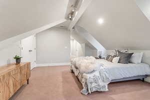 Carpeted bedroom featuring vaulted ceiling and rail lighting