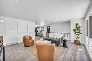 Living room featuring large windows, light hardwood style floors and crown molding.