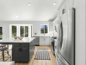 Kitchen with light cabinetry, a kitchen island, hardwood flooring, stainless steel appliances, and gray cabinets