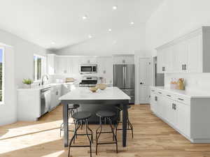 Kitchen featuring light hardwood flooring, a kitchen island, stainless steel appliances, high vaulted ceiling, and sink