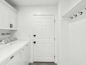 Clothes washing area with washer and dryer, cabinets, and light tile floors