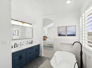 Bathroom featuring tile flooring, a tub, tile walls, vanity with extensive cabinet space, and dual sinks