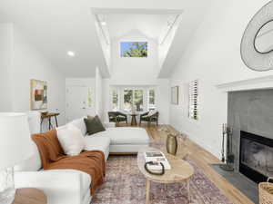 Living room featuring hardwood flooring, high vaulted ceiling, and a tile fireplace