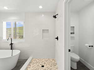 Bathroom featuring tile floors, a tile shower, toilet, and tile walls