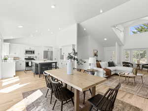 Dining space with high vaulted ceiling and light hardwood  flooring