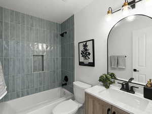 Full bathroom featuring tiled shower / bath, toilet, and vanity with extensive cabinet space