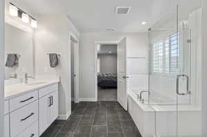 Bathroom featuring tile flooring, vanity with extensive cabinet space, and shower with separate bathtub