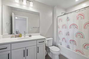 Full bathroom featuring shower / bath combo with shower curtain, vanity, toilet, and tile flooring