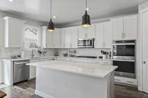 Kitchen with stainless steel appliances, sink, hardwood / wood-style flooring, and white cabinets