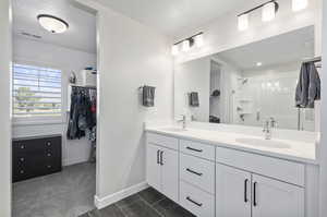 Bathroom featuring walk in shower, tile flooring, and double sink vanity