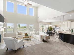 Living room with a high ceiling, a premium fireplace, ceiling fan